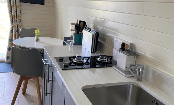 displaying table and chairs, sink, hob with all the utensils for self catering stay
